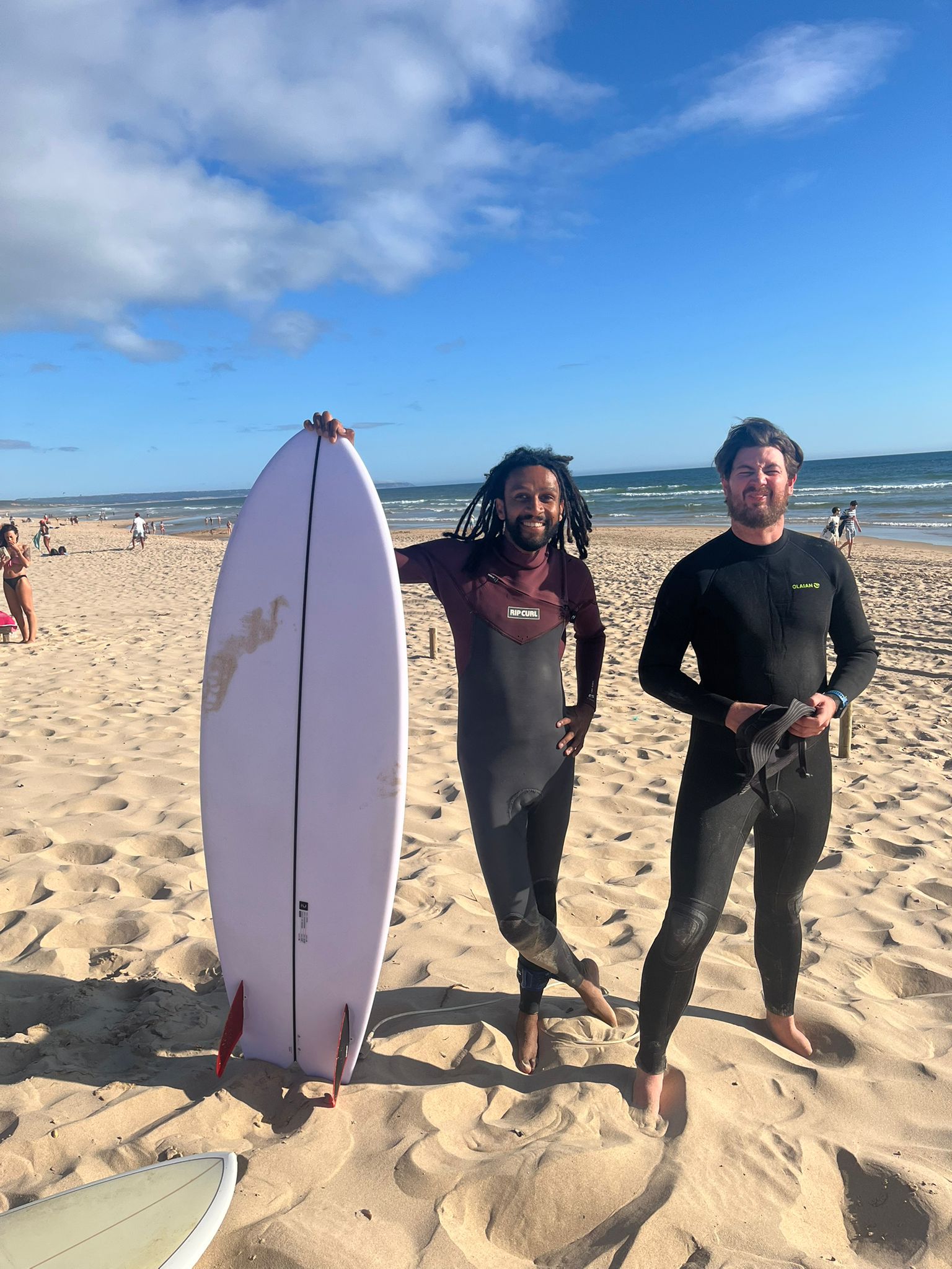 Deux amis sur la plage avec une planche de surf